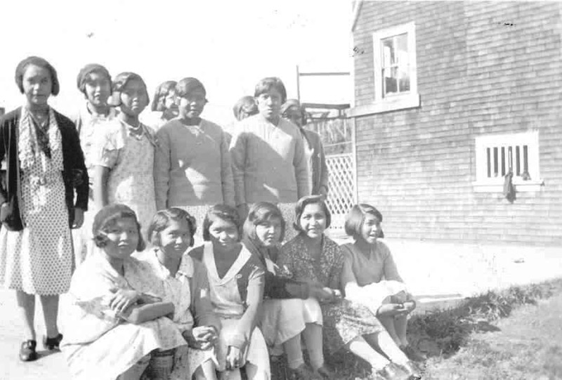 Group of youth standing and sitting outside near Ahousaht Residential School