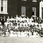 Youth from grades 1 to 6, seated and standing with staff in front of Alberni Residential School.