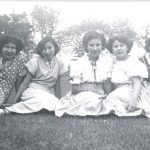 Five girls sitting together on a lawn