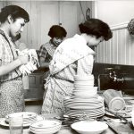 Youth washing, drying, and stacking dishes in a kitchen