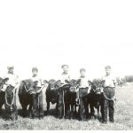 Five children standing with calves in a field