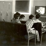 Children seated in two rows engrossed in watching tv