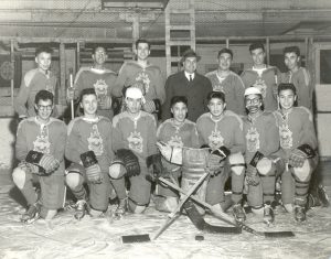 Portrait of youth in hockey gear and team uniforms with one person in a suit standing in the centre.