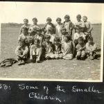 Group of younger children, some sitting and others standing, on the grounds of Morley Residential School. Caption below reads: Some of the smaller children.