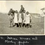Children standing in front of Indigenous person sitting on a horse. Caption below reads Indian women and Morley pupils.