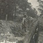 Students digging a trench, standing in a line overlooking the trench.