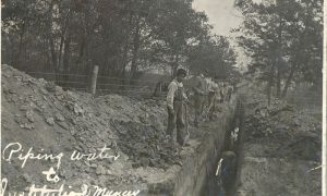 Students digging a trench, standing in a line overlooking the trench.