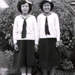 Two youth in Canadian Girls in Training uniforms standing posed for a photograph in front of File Hills Residential School.