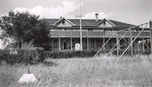 File Hills Residential School with swing set on the lawn in the foreground.