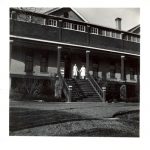 Miss Staples and Miss Baird at the top of the front steps of File Hills Residential School, taken from across the lawn.