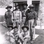 Group of youth in boy scout uniforms seated and standing posed for a photograph outside in front of File Hills Residential School.