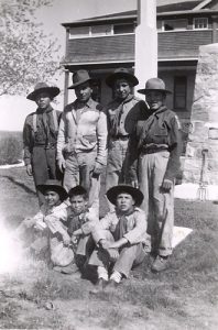 Group of youth in boy scout uniforms seated and standing posed for a photograph outside in front of File Hills Residential School.