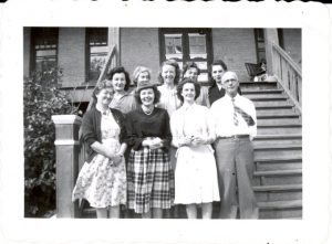 Group of faculty of File Hills Residential School standing posed for a photograph on the front steps.