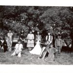 Children dressed in costume standing and sitting posed for a photo outdoors.
