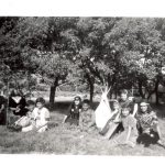 Students in theatrical costume sitting on grass.