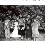 Students in theatrical costume standing in front of trees.