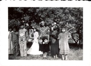 Group of children in costumes standing posed for a photograph outdoors.