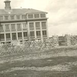 Exterior view of Norway House Residential School behind fence.