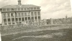 Exterior view of Norway House Residential School behind fence.