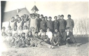 Group of reverend and children in front of building.