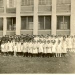 Children standing for a group photograph in front of the Norway House Residential School building. Students appear to be wearing uniforms.
