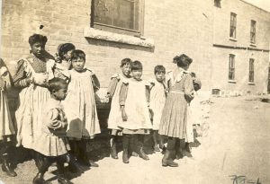 Group of children standing outside for a candid photo outside of Brandon Residential School wearing school uniforms.