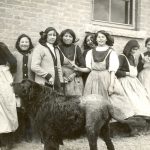 Group of youth wearing school uniforms standing for a candid photo, large dog in the foreground.