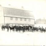 Horses standing outside barn in winter.
