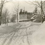 Road leading up to Brandon Residential School, with side of the building in background, taken in winter.
