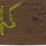 Wooden souvenir booklet cover with a yellow ribbon to hold pages together.