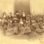 Children and staff from Port Simpson Residential School sitting posed for a portrait on steps.