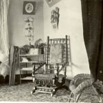 Corner of a sitting room with chair, bookcase, guitar case and wall décor