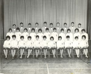Choir group portrait, three rows of youth seated and standing on stage
