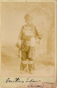 Portrait of Saulteaux person with tree background, caption reads 