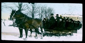 Children riding sleigh, pulled by two horses, hand coloured