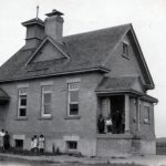 Students and staff standing outside schoolhouse, Muncey, Ontario.