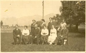 Staff, some standing and some seated on chairs, on the lawn posing for a group photograph.