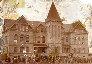 Image of the full building seen from a distance with all people gathered on the lawn and porch