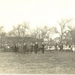 Moderator Right Rev. T.A. Moore plants a tree, with surrounding crowd on grounds of Coqualeetza Residential School