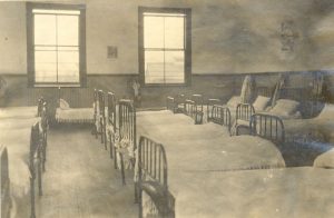 Dormitory showing three rows of made beds
