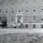 View of front of Alberni Residential School with car parked outside door.