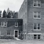 One side of Alberni Residential School with trees in the background.