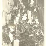 Large decorated Christmas tree with garland, tinsel and ornaments. Some presents beneath.