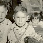 Four young children standing amongst desks