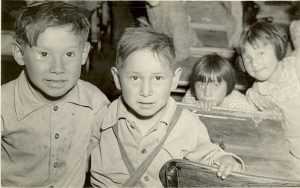 Four young children standing amongst desks