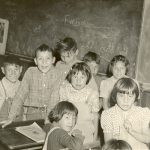 Children at desks in front of chalkboard