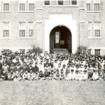 Large group of children with staff posed in from of Edmonton Residential School