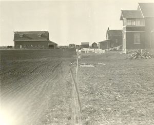 Road in the foreground and houses and buildings on either side as it leads into the background.