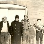 Three youths and a staff member standing in a row, wearing winter clothing outdoors.