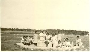 Little girls making mud pies in the sandbox at the Indian Boarding School, Norway House